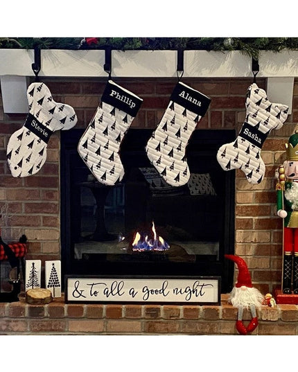 Black metal Christmas stocking holders from Industrial Farm Co holding four personalized stockings with tree pattern on br...