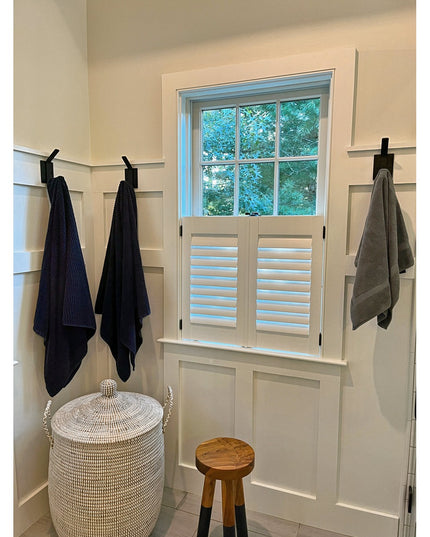 Black metal Elizabeth Wall Hooks by Industrial Farm Co mounted on white wainscoting holding navy and gray towels in bright...