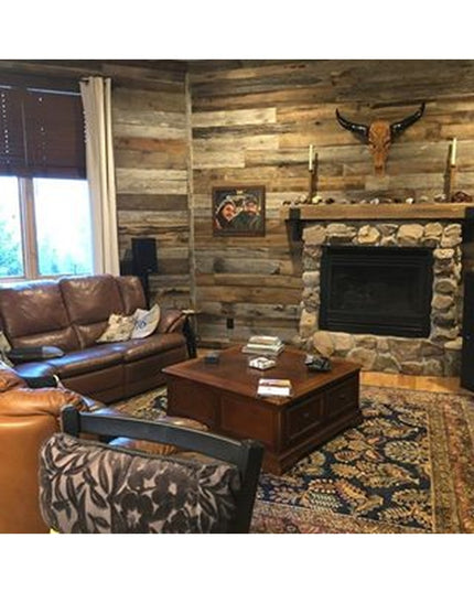 Rustic living room featuring stone fireplace with wooden mantel supported by metal brackets, leather furniture, and log ca...