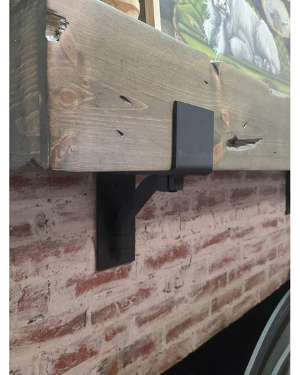 Heavy duty black steel Buffalo mantel bracket with square support bar mounted on rustic wood beam against exposed brick wa...