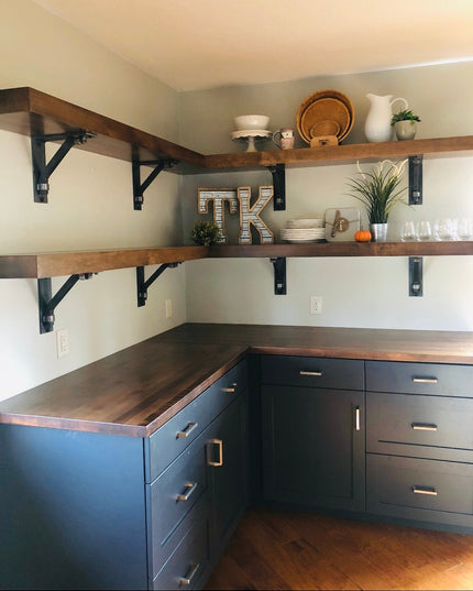 Dark navy blue kitchen cabinets with walnut wood countertops and open shelving supported by black Hornell Industrial Shelf...