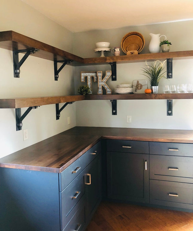 Dark navy blue kitchen cabinets with walnut wood countertops and open shelving supported by black Hornell Industrial Shelf...