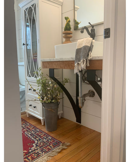 Black metal Rochester countertop brackets supporting white marble vanity with wooden base in modern farmhouse bathroom by ...