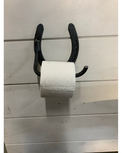 Black horseshoe toilet paper holder mounted on white shiplap wall holding white toilet paper roll - The Tierney by Industr...