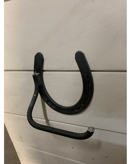 Black iron horseshoe toilet paper holder mounted on white wall by Industrial Farm Co, rustic farmhouse bathroom hardware w...