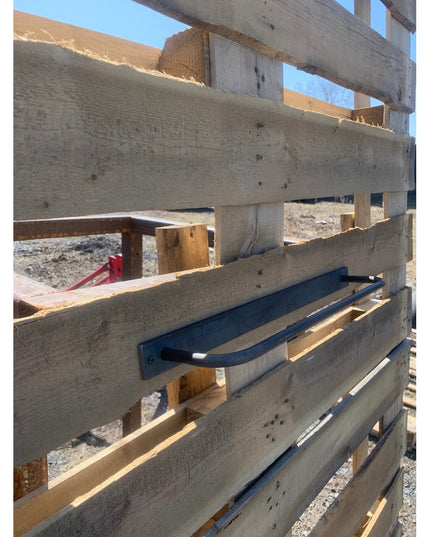 Black metal Oswego Modern Bathroom Towel Bar by Industrial Farm Co mounted on weathered wood construction frame outdoors