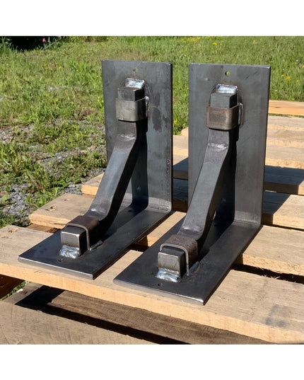 Two black metal Rosamond Shelf Supports by Industrial Farm Co with triangular brackets and bolt hardware displayed on wood...