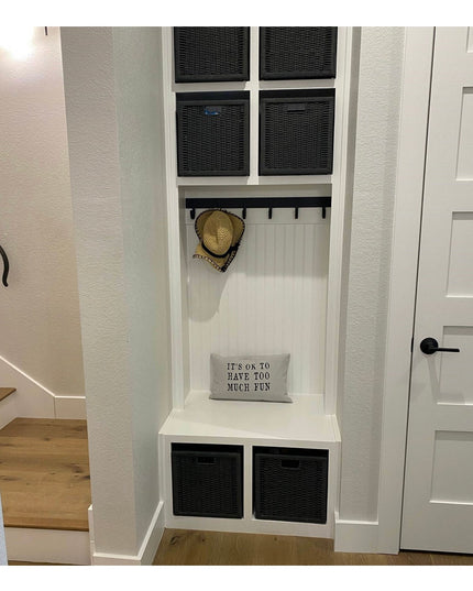 White built-in mudroom storage unit with black wicker baskets, coat hooks, bench seating, and beadboard backing from Indus...
