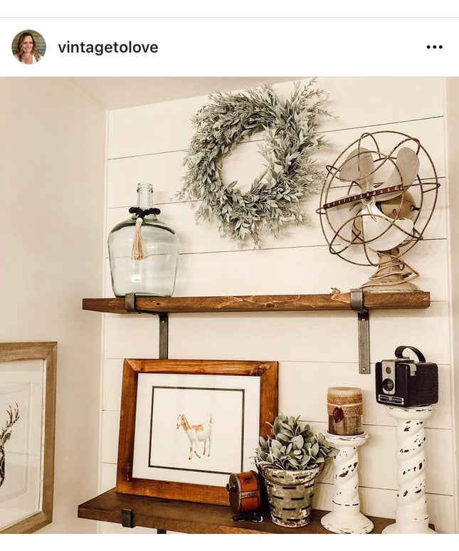 Rustic wooden shelves with black iron Z-style brackets displaying vintage farmhouse decor items against white shiplap wall