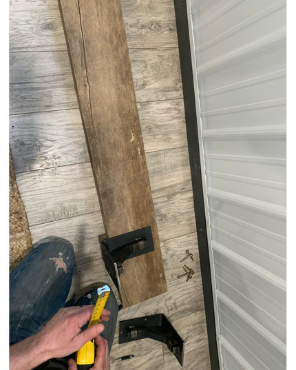 Person installing black metal Rosamond Shelf Supports on wood beam using yellow level tool, Industrial Farm Co floating sh...
