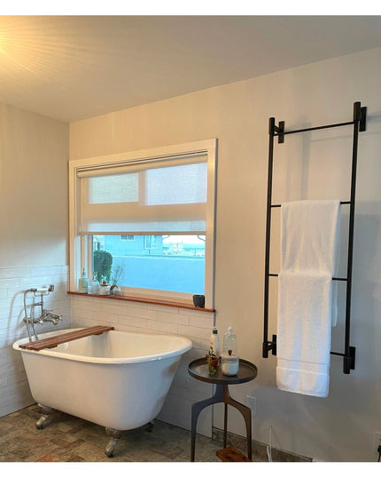 Black metal Wall Mounted Ossit Ladder by Industrial Farm Co displaying white towels in modern bathroom with clawfoot tub