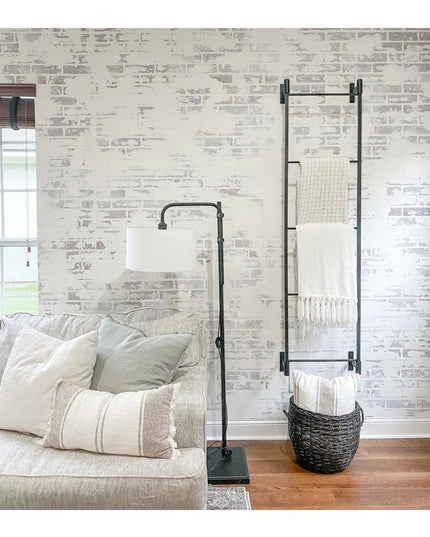 Black industrial wall-mounted Ossit ladder by Industrial Farm Co displaying blankets in modern living room with whitewashe...