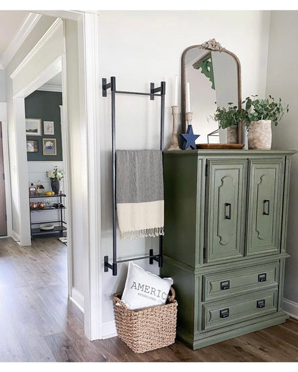 Black metal wall mounted Ossit ladder from Industrial Farm Co displaying gray and white striped throw blanket in modern fa...