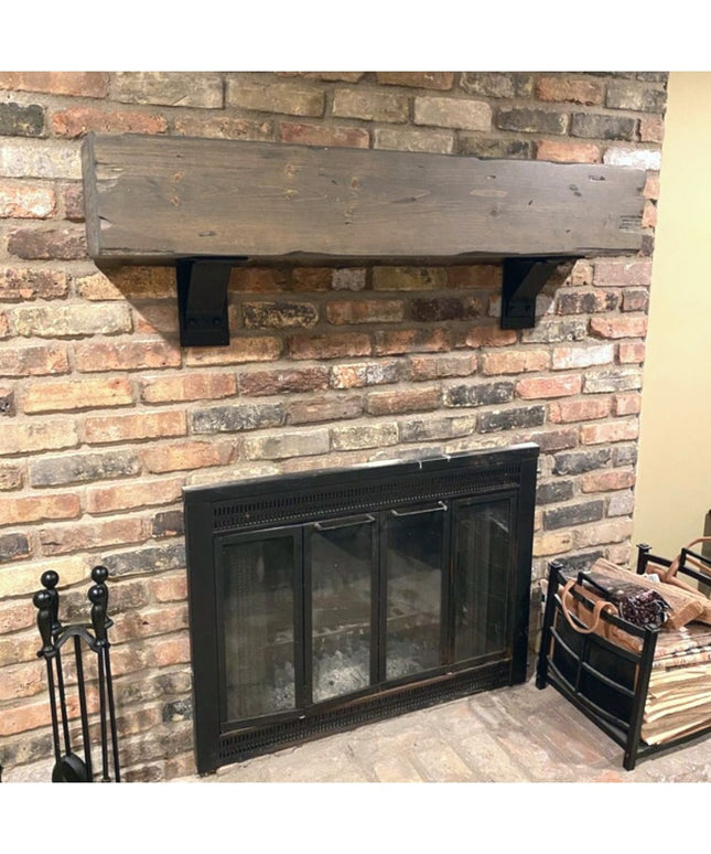 Rustic wood mantel shelf with black Parish Style Bracket Support from Industrial Farm Co mounted on brick fireplace wall