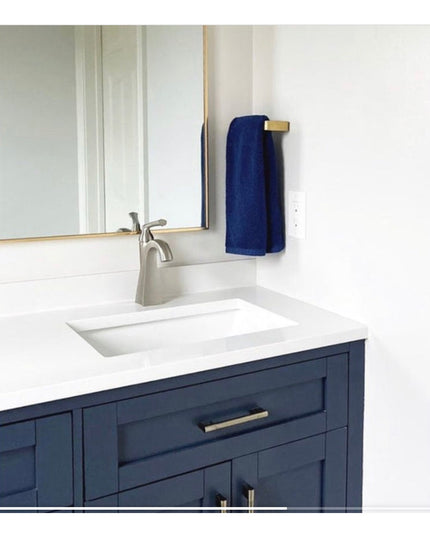 Industrial Farm Co Emma brass towel holder mounted on bathroom vanity with navy blue towel hanging from gold-finished door...