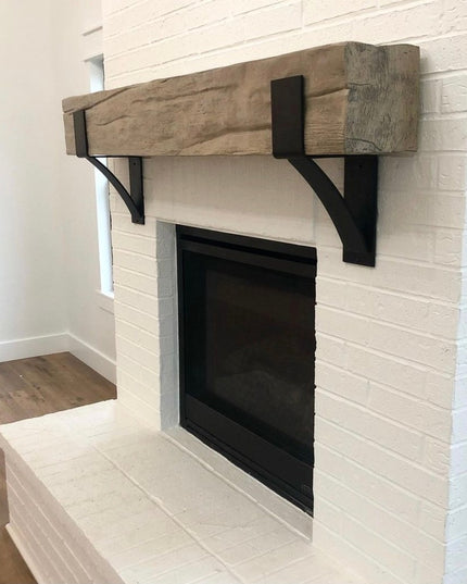Kudlick Farmhouse black metal mantel brackets supporting rustic wood beam above white brick fireplace by Industrial Farm Co
