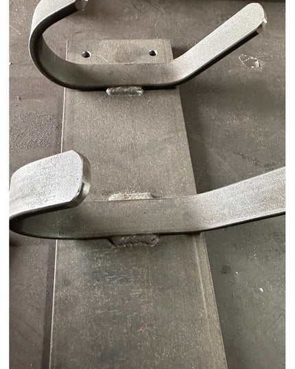 Industrial Farm Co Riseform black metal wall mounted coat rack with curved hooks on gray concrete wall