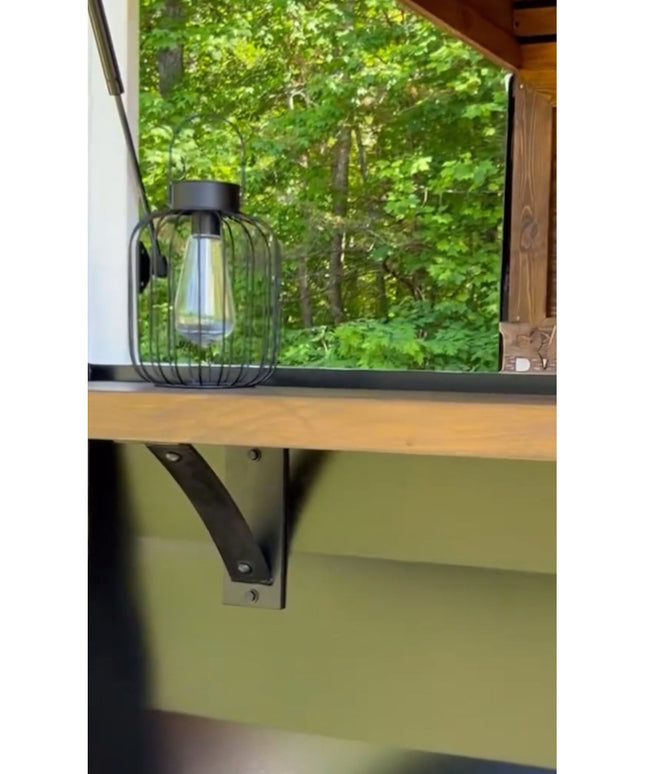 Industrial black metal Cortland 3 inch shelf bracket with rivets supporting wood shelf under window with decorative lantern