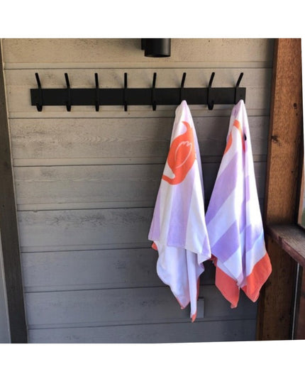 Black metal Cooperstown Double Hook Coat Rack mounted on gray shiplap wall with colorful tea towels hanging from two hooks