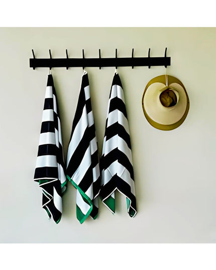 Black wall-mounted Cooperstown Double Hook Coat Rack by Industrial Farm Co with 9 hooks holding striped towels and straw h...