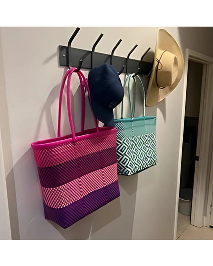 Black metal Cooperstown Double Hook Coat Rack mounted on white wall holding colorful tote bags, navy cap, and tan hat