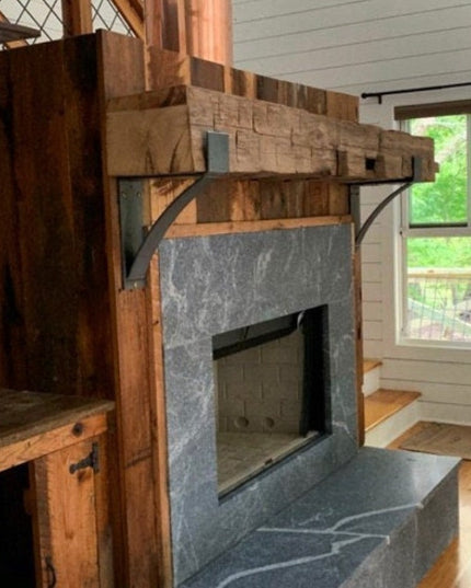 Rustic wooden Kudlick Farmhouse Mantel Brackets supporting stone fireplace mantel with metal accents in white cabin interior