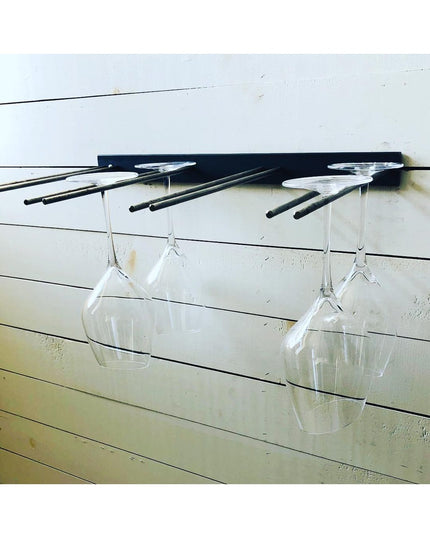 White Plains wine glass rack by Industrial Farm Co mounted on white shiplap wall, displaying clear wine glasses hanging up...