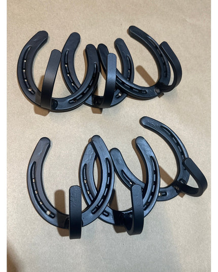 Black metal horseshoe wall hooks by Industrial Farm Co arranged in two rows on beige surface, showing heavy duty farmhouse...