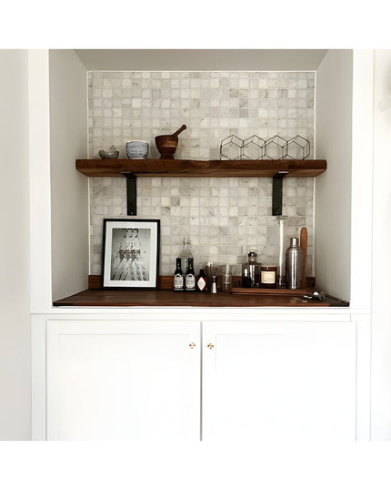 Modern built-in bar nook with white marble mosaic tile backsplash, dark wood floating shelves on black steel brackets, whi...