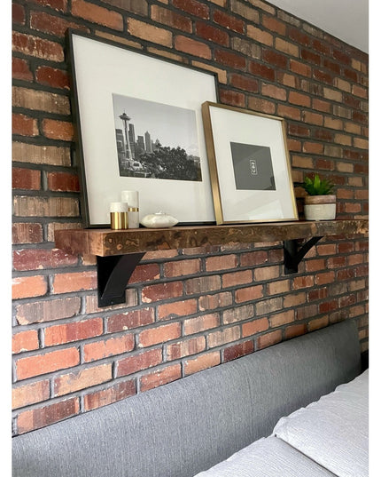 Black steel Albany Industrial shelf bracket supporting reclaimed wood shelf on exposed brick wall with framed artwork and ...