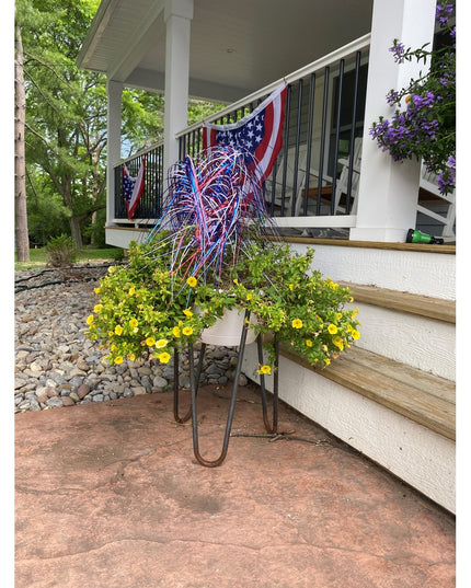 Black metal Dorio Raised Planter by Industrial Farm Co with yellow flowers and patriotic decorations on front porch steps