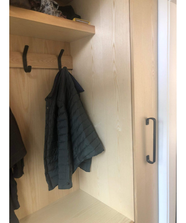 Black Long Beach Handle door pull by Industrial Farm Co mounted on light wood closet door with hanging jacket and storage ...