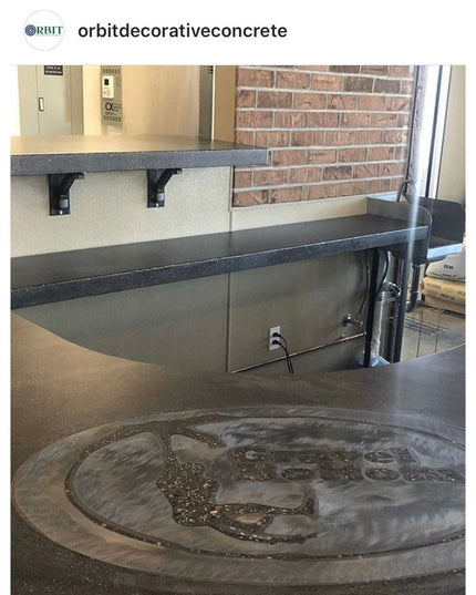 Dark concrete countertop with circular sink design featuring decorative pattern, Industrial Farm Co Hornell shelf supports...