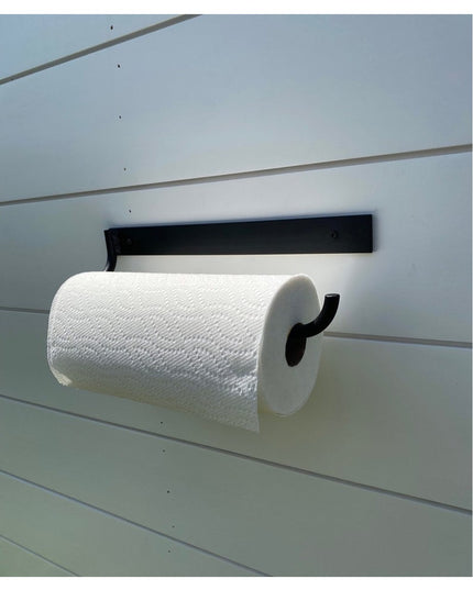 Black metal Hyde Hall Paper Towel Holder by Industrial Farm Co mounted on white slatwall displaying white paper towel roll