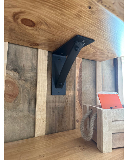 Black metal Cortland 3" shelf bracket with rivets by Industrial Farm Co supporting rustic wood shelf in farmhouse interior
