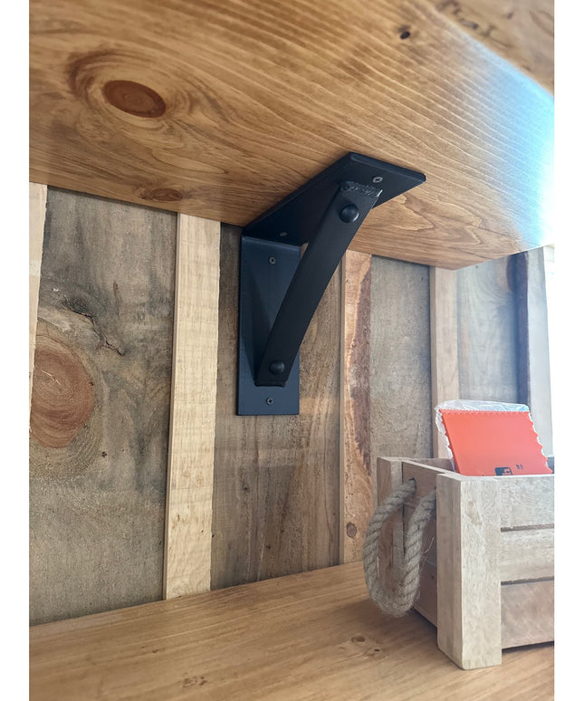Black metal Cortland 3" shelf bracket with rivets by Industrial Farm Co supporting rustic wood shelf in farmhouse interior