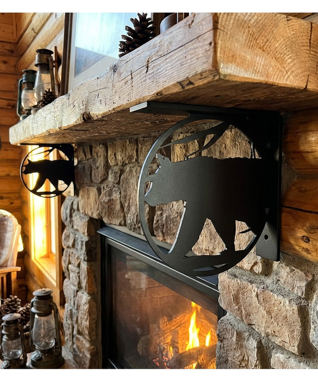 Black metal bear silhouette L-bracket shelf support holding rustic wood mantel above stone fireplace in log cabin interior