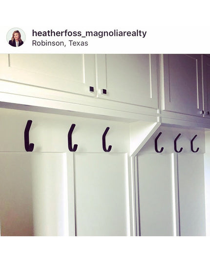 Black metal Henrietta 1" Wide Double Hooks mounted on white kitchen cabinet doors and walls by Industrial Farm Co, showing...