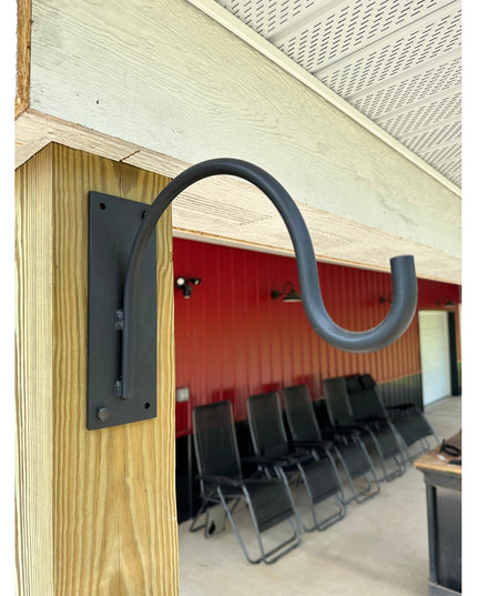 Black metal Gregory Shepherd Hook by Industrial Farm Co mounted on wooden beam in modern interior with red corrugated meta...