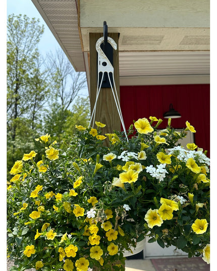 White Industrial Farm Co Gregory Shepherd Hook holding yellow petunia hanging basket on covered porch with red door