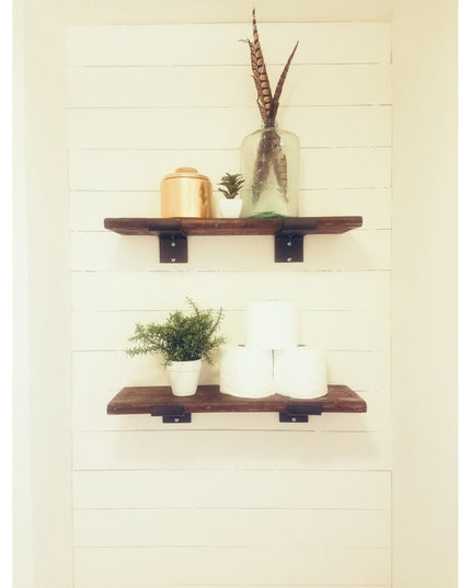 Rustic wooden floating shelves with black metal Z-style brackets mounted on white shiplap wall, displaying plants and deco...