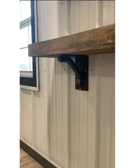 Black metal Rosamond shelf bracket supporting reclaimed wood shelf against white wainscoting wall by Industrial Farm Co
