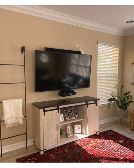 Black metal Brielle Top Mounted Blanket Ladder by Industrial Farm Co displaying white throw blanket in modern living room