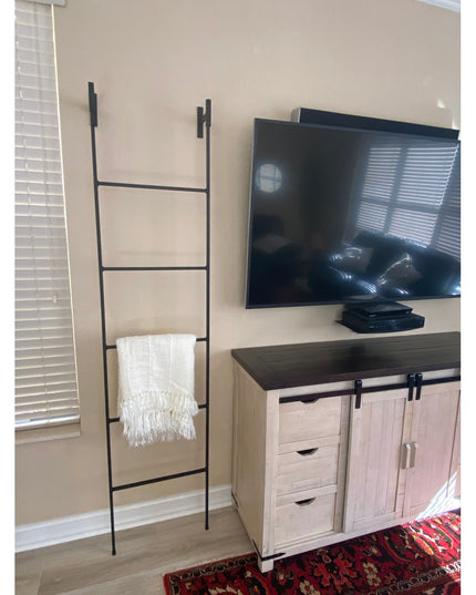 Black metal Brielle Top Mounted Blanket Ladder by Industrial Farm Co displaying white throw blanket in modern living room