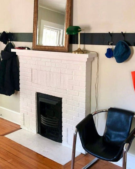 Black metal wall-mounted Bo Style Lodge Coat Rack by Industrial Farm Co installed above white brick fireplace with coats, ...
