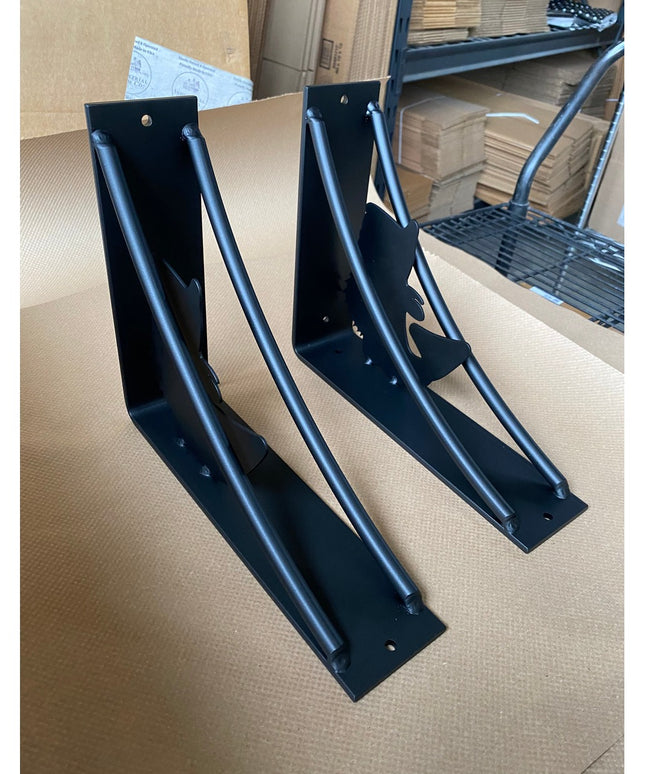 Two black metal heavy-duty large mouth bass shelf brackets with curved support arms displayed on cardboard surface in ware...