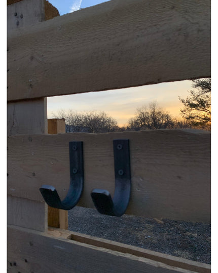 Two black J-shaped Kinnley 1" Wide Wall Hooks by Industrial Farm Co mounted on concrete beam, industrial style metal hooks...