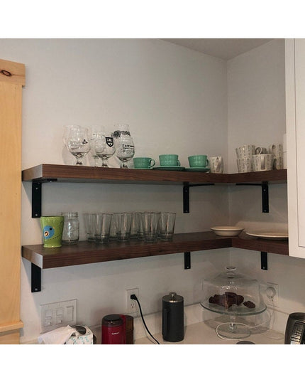 Dark wood floating shelves with black metal L-brackets displaying glassware and dishes in modern kitchen corner - Lucas L ...