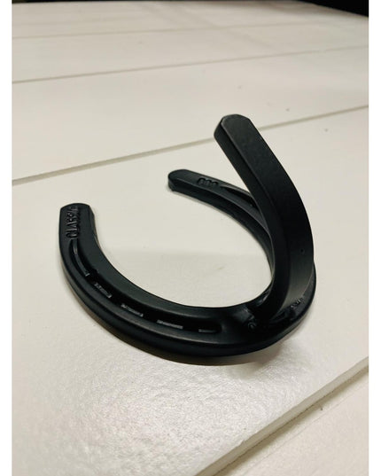 Black metal horseshoe wall hook with mounting holes on white wooden surface - Industrial Farm Co heavy duty farmhouse west...