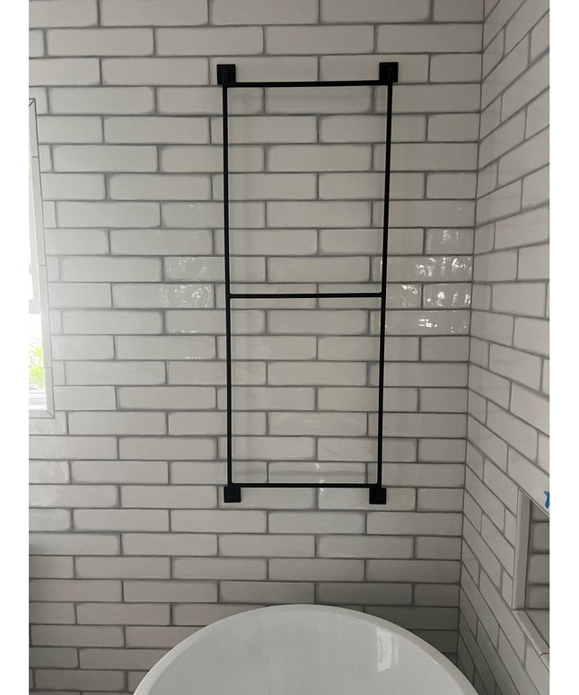 Black metal Arianna Wall Mounted Ladder by Industrial Farm Co displayed against white subway tile bathroom wall above toilet